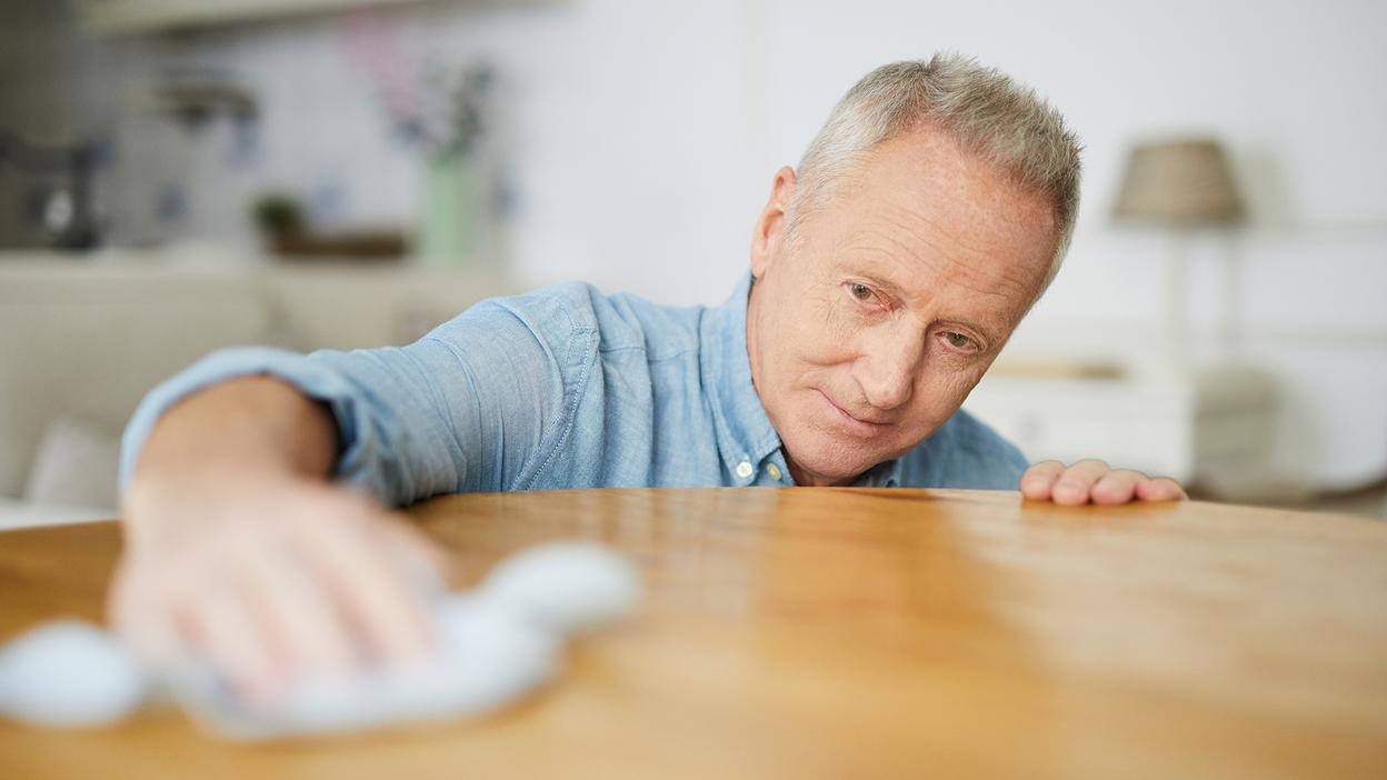 Mann reinigt Holztisch